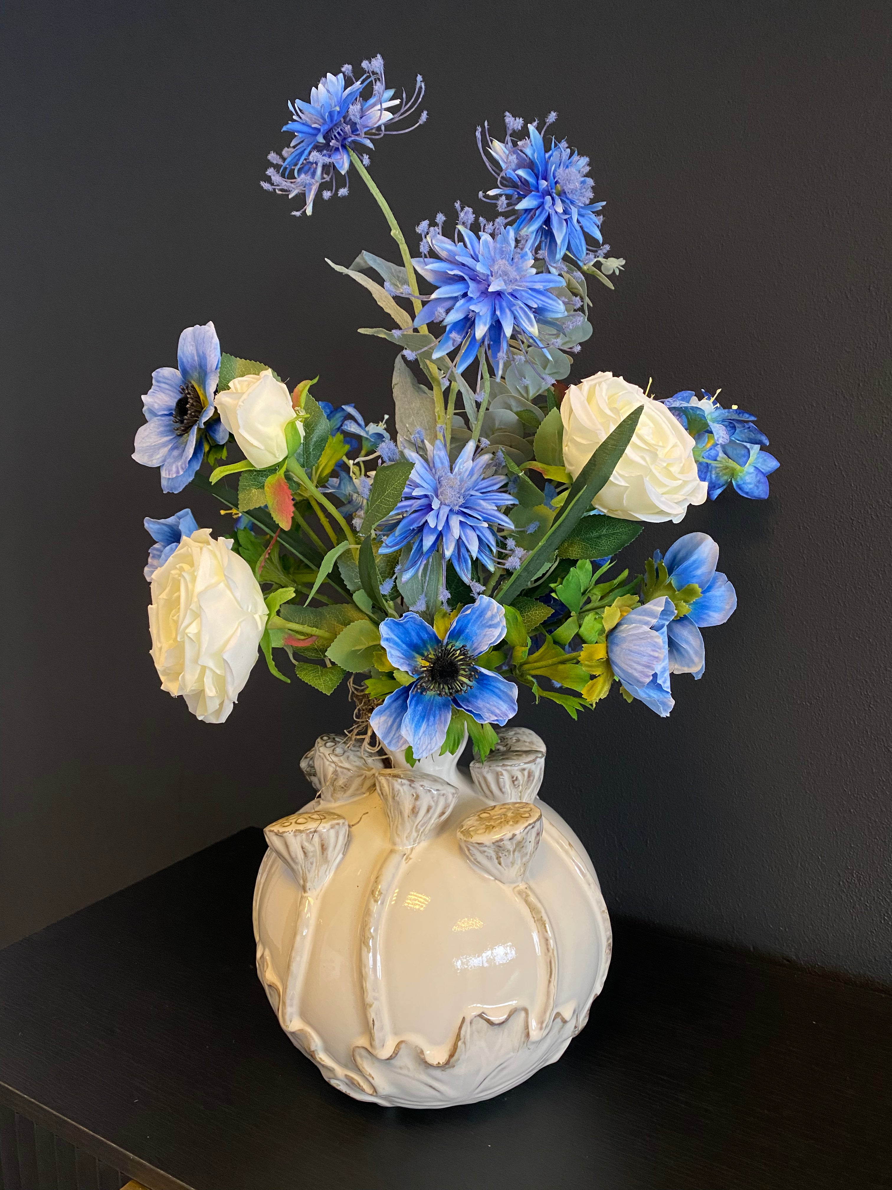Luxe blauw-wit kunstbloemstuk met blauwe bloemen, witte rozen en een decoratieve crèmekleurige vaas met goudkleurige details.