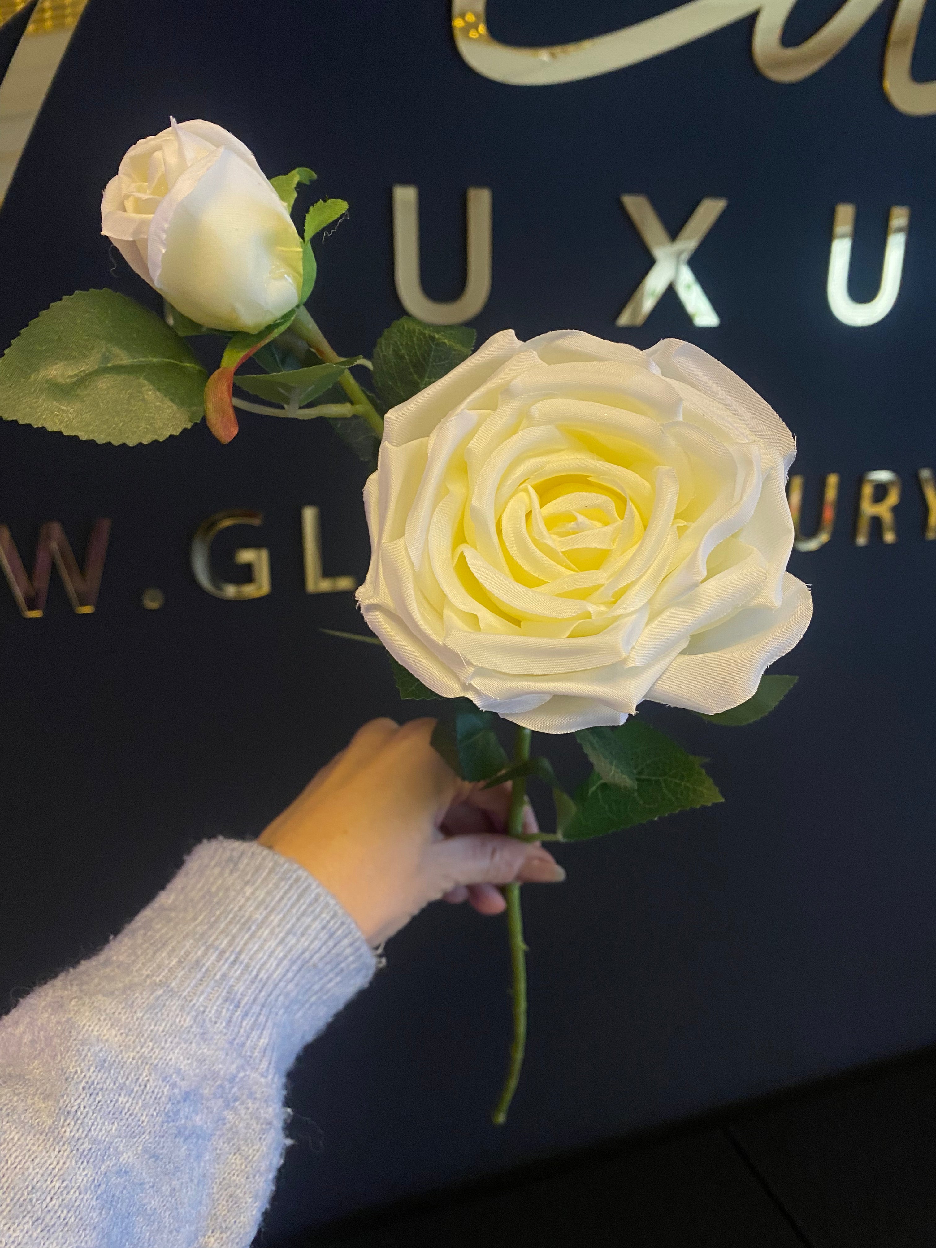 Crème witte kunstroos van 65 cm met een grote geopende roos, rozenknop en groene bladeren.